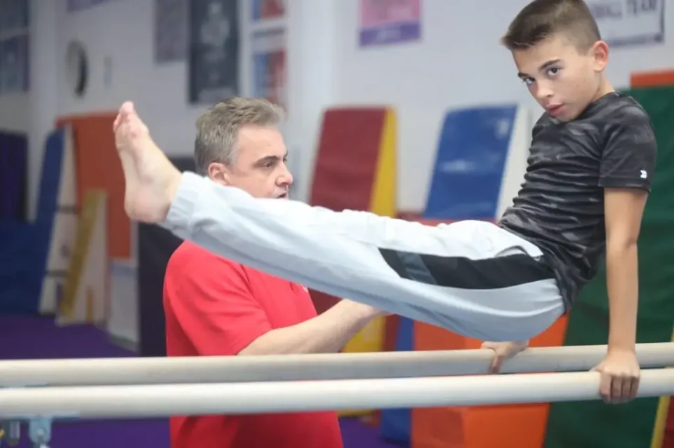 Boy practicing gymnastics with instructor.