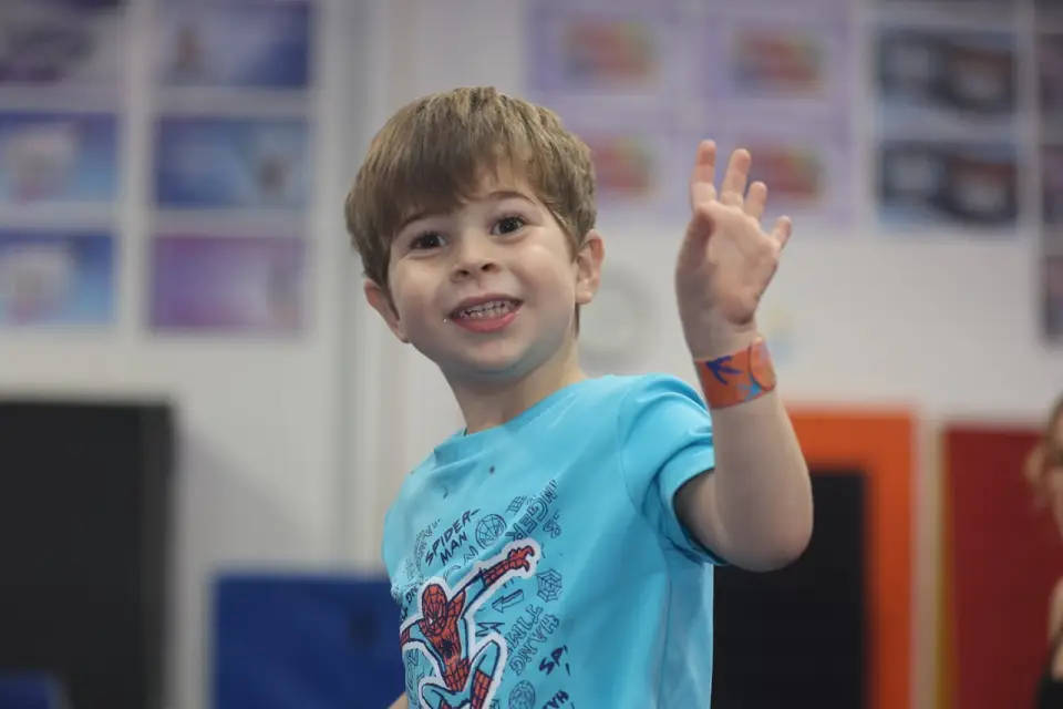 Smiling child waving in gym